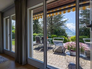 A room with large sliding glass doors leading to an outdoor patio with a table and chairs. - Schwyz, (Schwyz), by Interhome (Seewen SZ)