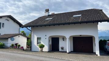 Ein zweistöckiges Haus mit einem Ziegeldach, einem Hauseingang mit einer dunklen Tür und einem kleinen Balkon mit einem Blumentopf.