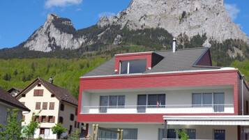 Ein zweistöckiges Gebäude mit roter und weißer Fassade, einem Balkon und Blick auf einen Berg.