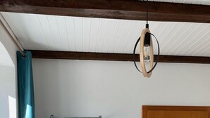 Ett rum med en dörr av trä, en hängande lampa, en klädställning med kläder, en bänk och ett element.