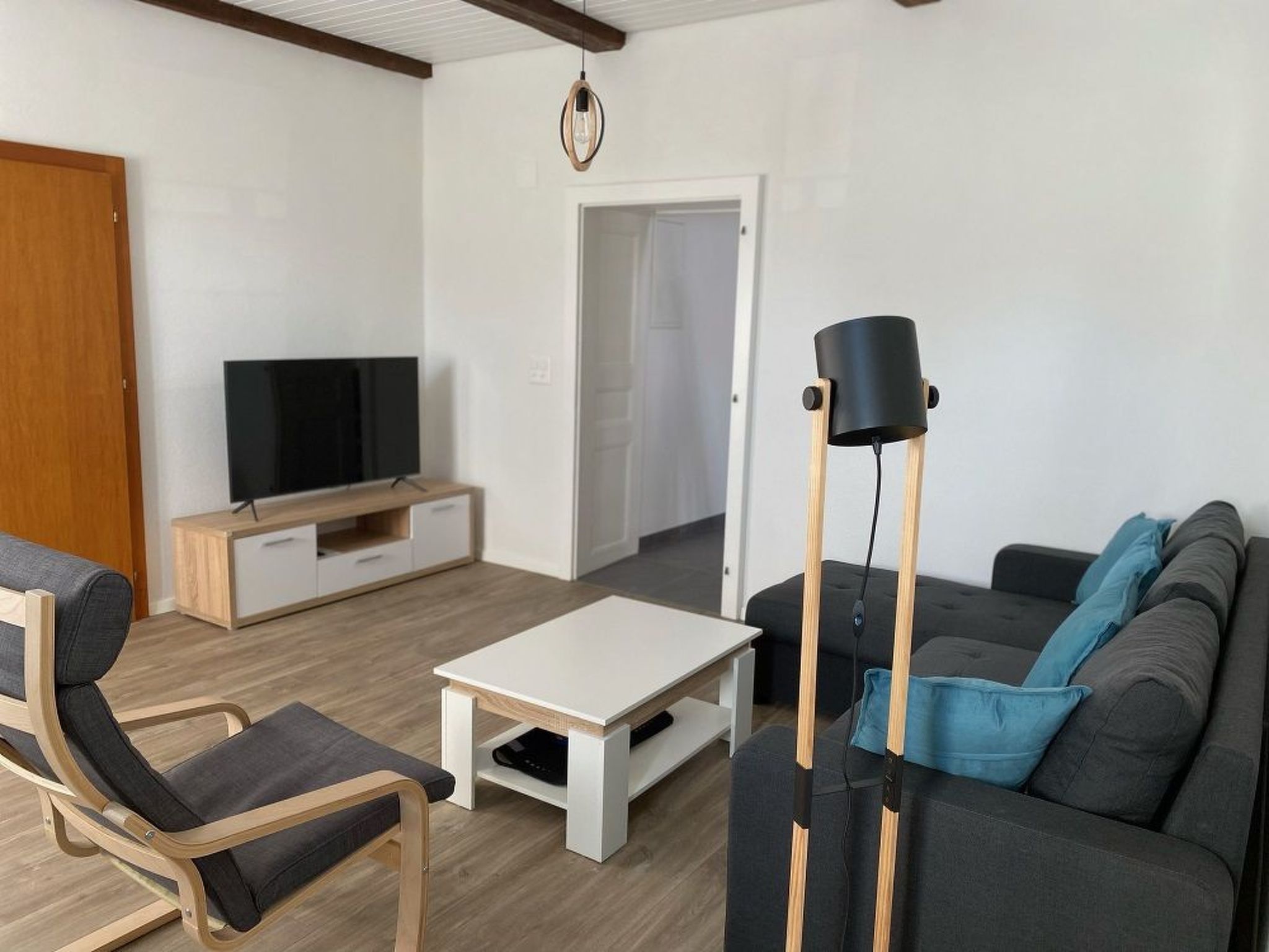 A modern living room with a flat-screen TV, a sofa, a coffee table, and a floor lamp.