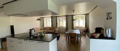 A modern kitchen with a central island, a dining area with a table and chairs, and a living space with a sofa.