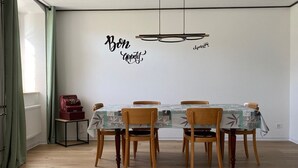 En matplats med ett bord dukat för fyra personer, trästolar, en gammal radio och en vägg med inspirerande citat.