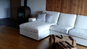 A modern living room with a white sectional sofa, a fireplace, and a rustic wooden coffee table. - Appartement - Serena, (Courtetelle), by Interhome (Courtételle)