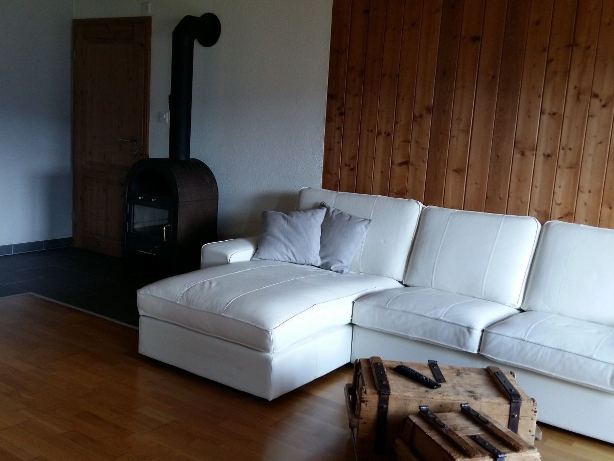 A modern living room with a white sectional sofa, a fireplace, and a wooden floor.