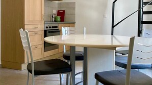A modern kitchen with wooden cabinets, a white countertop, and a dining table with four chairs. - Gîte - Le Cras, (Soubey), by Interhome (Soubey)