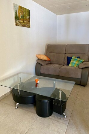A modern living room with a glass coffee table, a sofa, and a painting on the wall. - Gîte - Le Cras, (Soubey), by Interhome (Soubey)