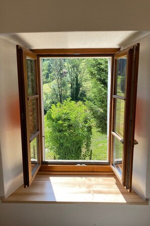 Ein Zimmer mit großem Fenster und Blick auf eine grüne Landschaft.