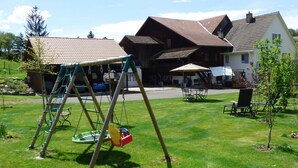 A residential area with a swing set, a lawn, and a house with a tiled roof. - Studio - Le Râtelier, (Coeuve), by Interhome (Coeuve)