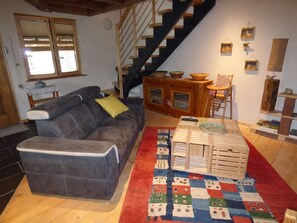 Ein Wohnzimmer mit einer Couch, einem Holzschrank, einer Treppe und einem roten und weißen Teppich mit Muster.
