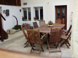An outdoor patio with a wooden table and chairs, surrounded by potted plants and a rustic wooden chair. - Studio - Le Râtelier, (Coeuve), by Interhome (Coeuve)