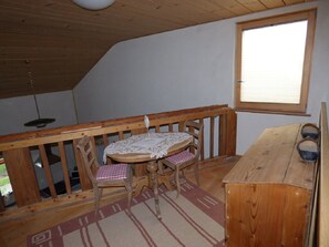 Ein kleiner Raum mit Holztisch und -stühlen, einem Fenster und einer hölzernen Bank.