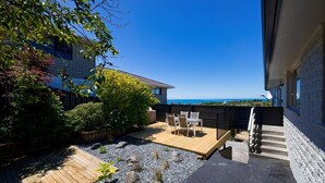 Een patio met een houten terras, zitplaatsen en uitzicht op zee.