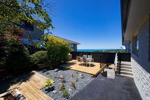 Eine Terrassenanlage mit Holzdeck, Sitzgelegenheiten und Blick aufs Meer.