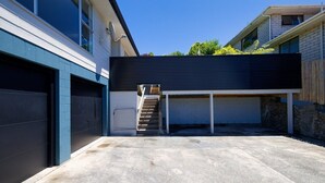 Een moderne garage met een betonnen vloer en een houten trap die naar een overdekt gebied leidt.
