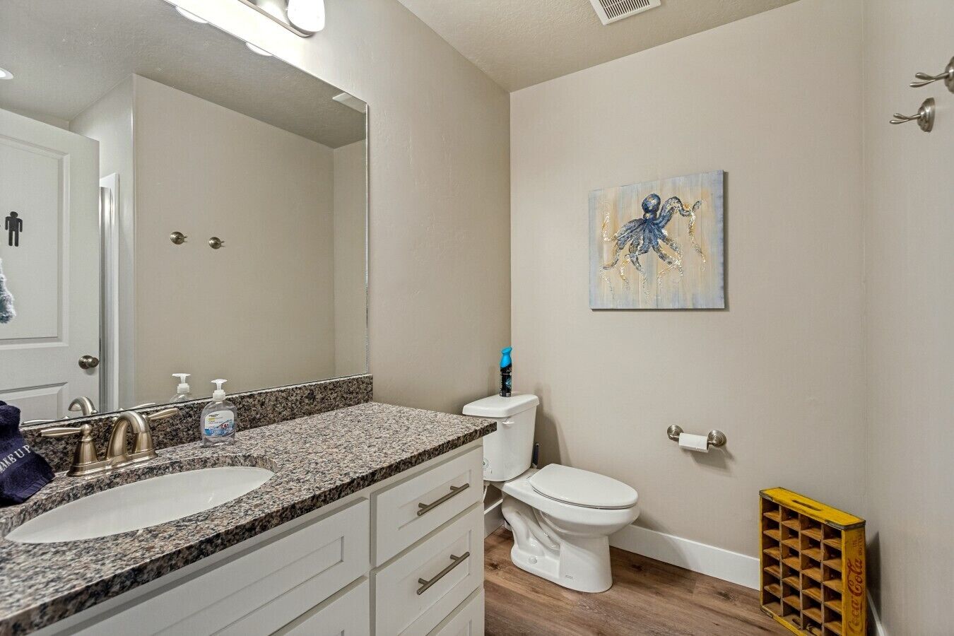 Baño con encimera de granito, dos lavamanos, inodoro y ducha.