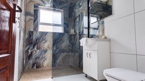 Un baño con salpicadero de mármol, un lavabo blanco y un espejo encima.