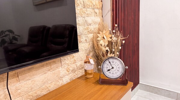 Una mesa de madera con un reloj, una botella y plantas secas.