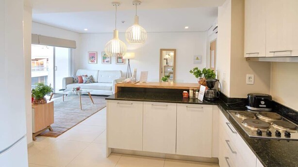 A modern kitchen with a central island, white cabinetry, and a gas stove. - Corporate Stays Edificio Pilar - N2A2 (Asunción)