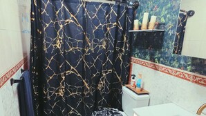 Ein Badezimmer mit Duschvorhang, Toilette, Waschbecken und einem dekorativen Spiegel.