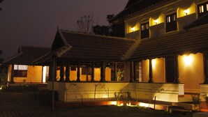A traditional building with multiple rooms, a covered porch, and a well-lit entrance. - SURYAMANGALAM HERITAGE (Ottapalam)