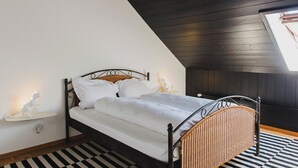Ein Schlafzimmer mit einem Bett, einem Nachttisch, einer Lampe und einem Fenster.