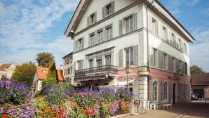 Ein mehrstöckiges Gebäude mit einem Balkon, umgeben von einer Vielzahl bunter Blumen.
