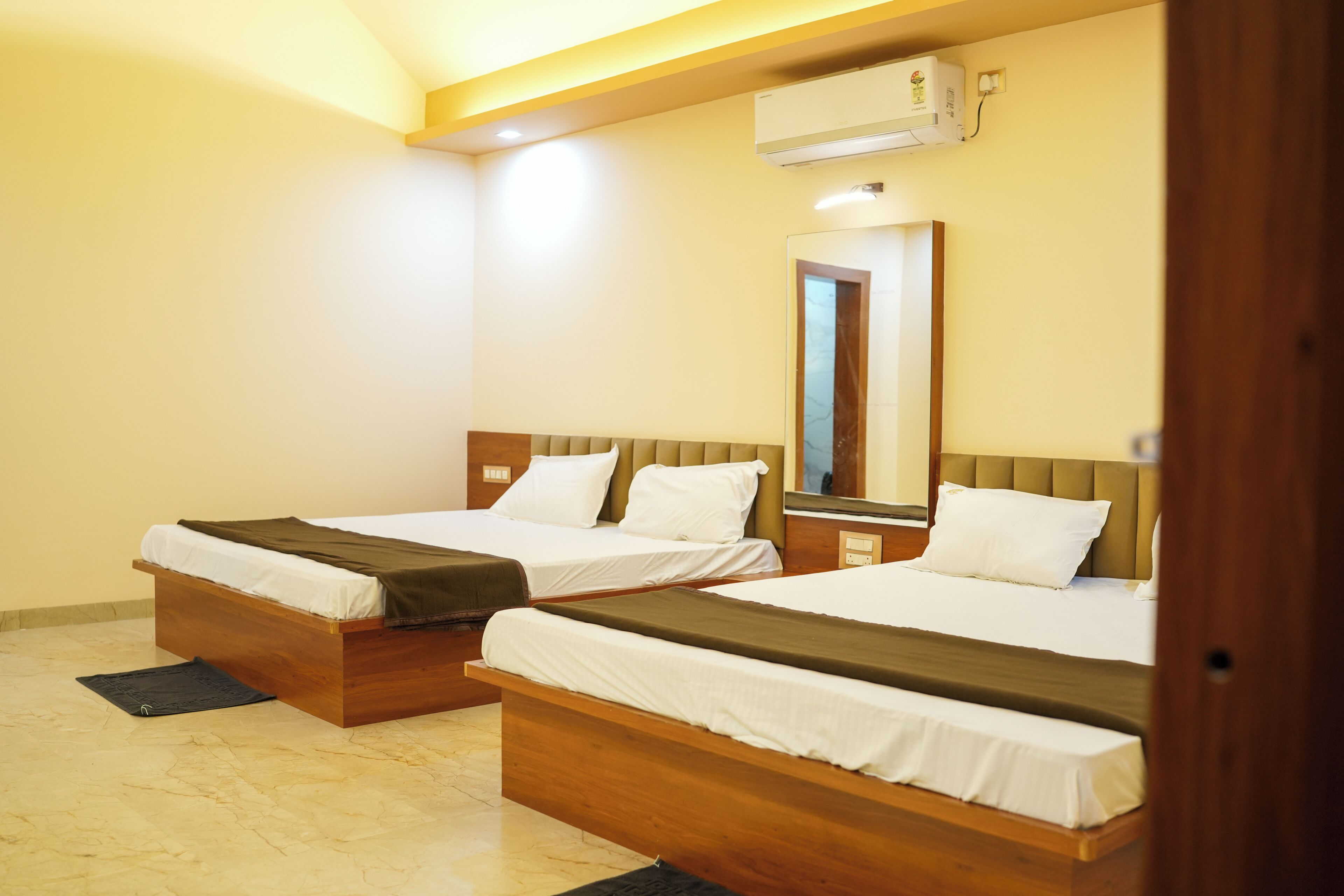 Een hotelkamer met twee houten bedden, een marmeren vloer, een airconditioning en een spiegel aan de muur.