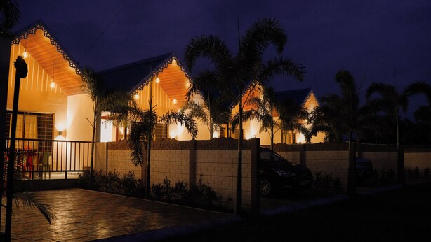 A building with a tiled entrance, a gated driveway, and palm trees. - Vrindavan Guest house  (Ambegaon)