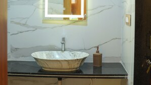 A bathroom with a marble sink, a mirror, and a black countertop. - Vrindavan Guest house  (Ambegaon)