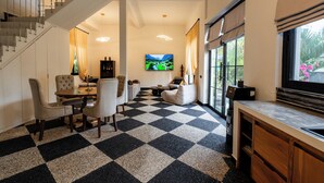 A modern interior with a checkered floor, a dining area, a sofa, a TV, and a kitchen area. - Orfeas Villas 2 Canggu Villa 2BR Pool (Canggu)
