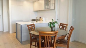 Une cuisine moderne avec des meubles blancs, un îlot central et une table à manger avec des chaises.