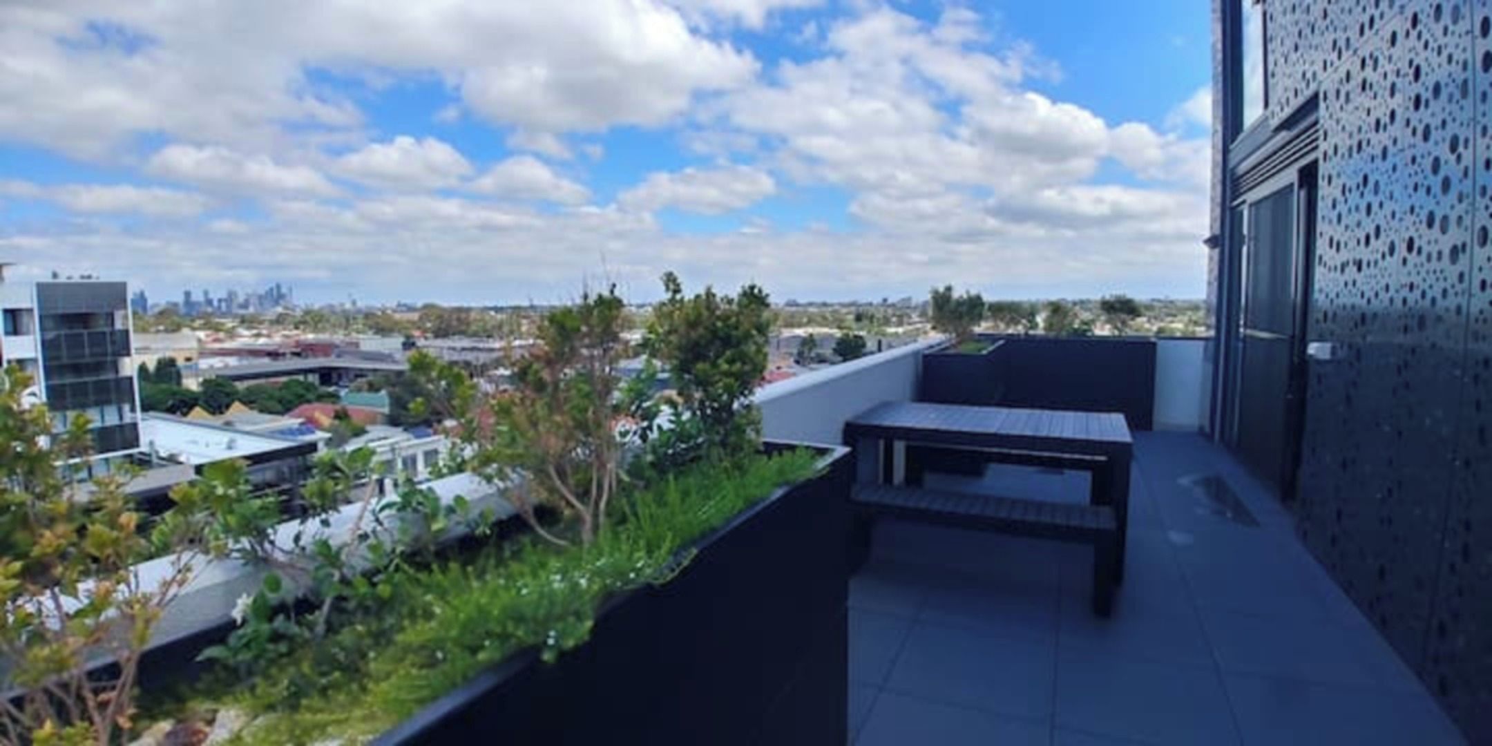 Una terraza en la azotea con vistas a un paisaje urbano, un área de estar y un edificio con fachada perforada.