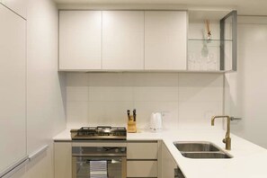 A modern kitchen with white cabinets, a stainless steel sink, and a gas stove.