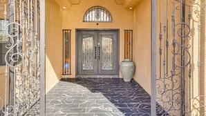 A building entrance with a double door, a large vase, and decorative ironwork. - Resort-Style Home with Backyard & Heated Pool : A Luxe Tucson Home (Tucson)