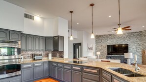A modern kitchen with granite countertops, a built-in oven, and a large island with a sink. - Resort-Style Home with Backyard & Heated Pool : A Luxe Tucson Home (Tucson)