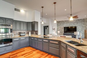 Eine moderne Küche mit Granit-Arbeitsplatten, einem eingebauten Backofen und einer großen Kochinsel mit Spüle.