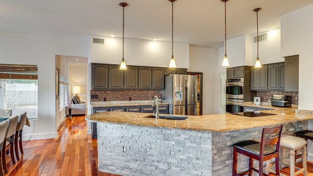 A modern kitchen with granite countertops, stainless steel appliances, and pendant lighting. - Resort-Style Home with Backyard & Heated Pool : A Luxe Tucson Home (Tucson)