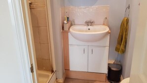 A bathroom with a white sink, a mirror above it, a towel hanging on a rack, and a toilet.