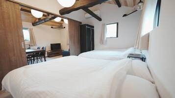 A bedroom with two beds, a desk, a chair, and a wardrobe.