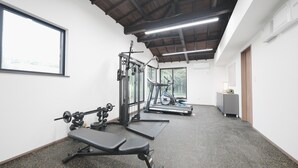 A gym with weightlifting equipment, treadmills, and a bench.