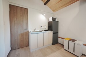 Cocina compacta con puerta de madera, pileta integrada, microondas y refrigerador.