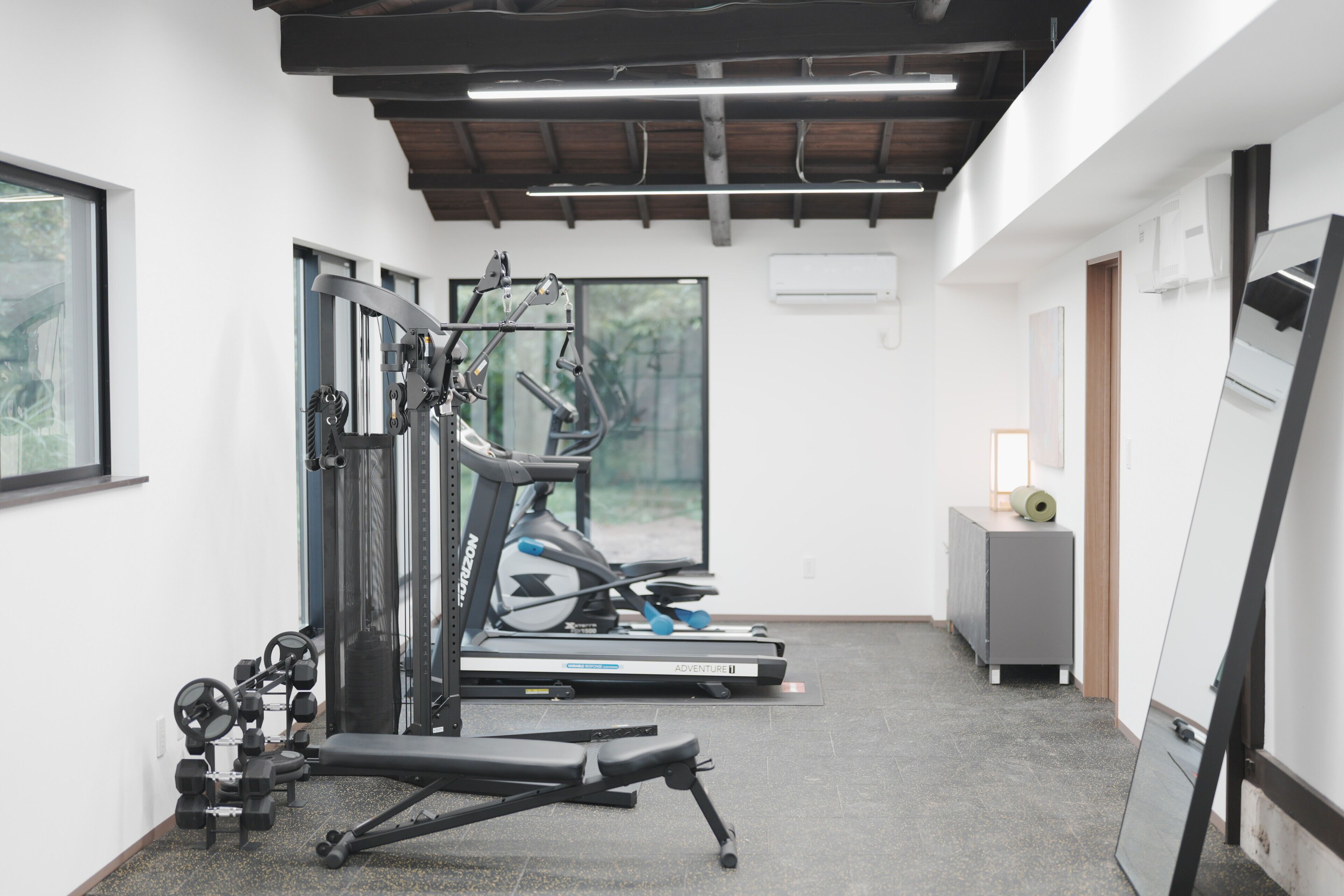Een sportschool met trainingsapparatuur, loopbanden en een bankje.