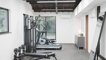 Een sportschool met trainingsapparatuur, loopbanden en een bankje.