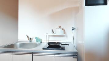 A compact kitchen with a sink, a stove, and a white refrigerator.
