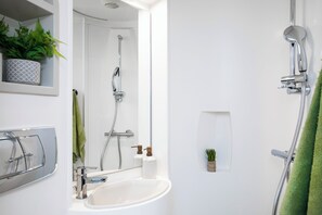 A bathroom with a white sink, a mirror, a shower, and a green towel. - Student Only Arbour House (London)