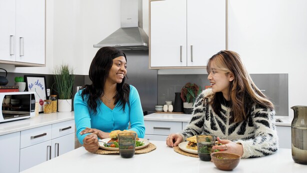 Una cocina moderna con armarios blancos, una campana extractora de acero inoxidable y un microondas.