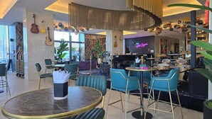 Ett modernt loungeområde med en bar, sittplatser och en scen med musikinstrument.