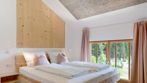 A modern bedroom with a wooden bed frame, a built-in bench, and a large window with curtains.