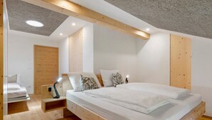 Un dormitorio con estructura de cama de madera, una mesita de noche con lámpara y un armario de madera.